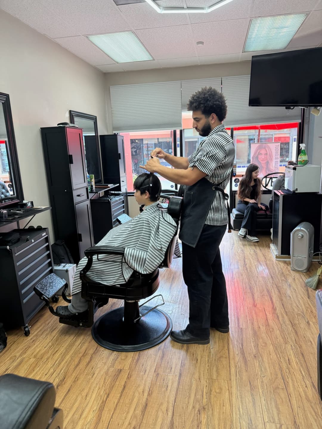 Barber cutting and styling a client’s hair inside Zion Salon & Barber Shop in National City, California.